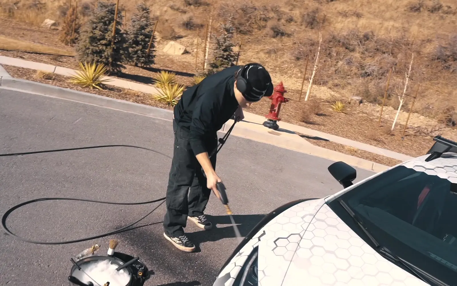 A detailer washing the hex-liveried hood of a Lamborghini Sterrato