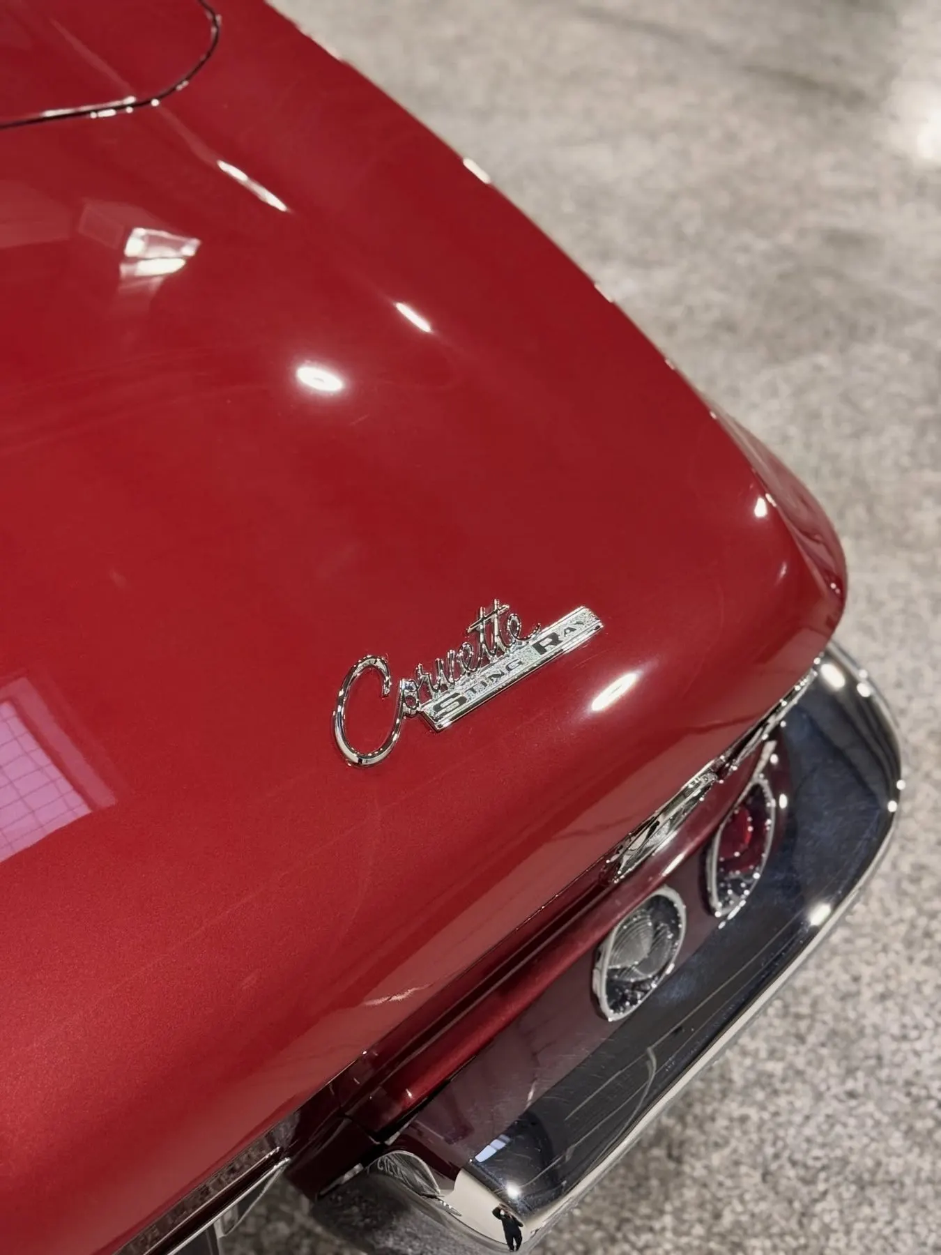 The deep red rear quarter of a kept classic Corvette, badge and chrome still sharp