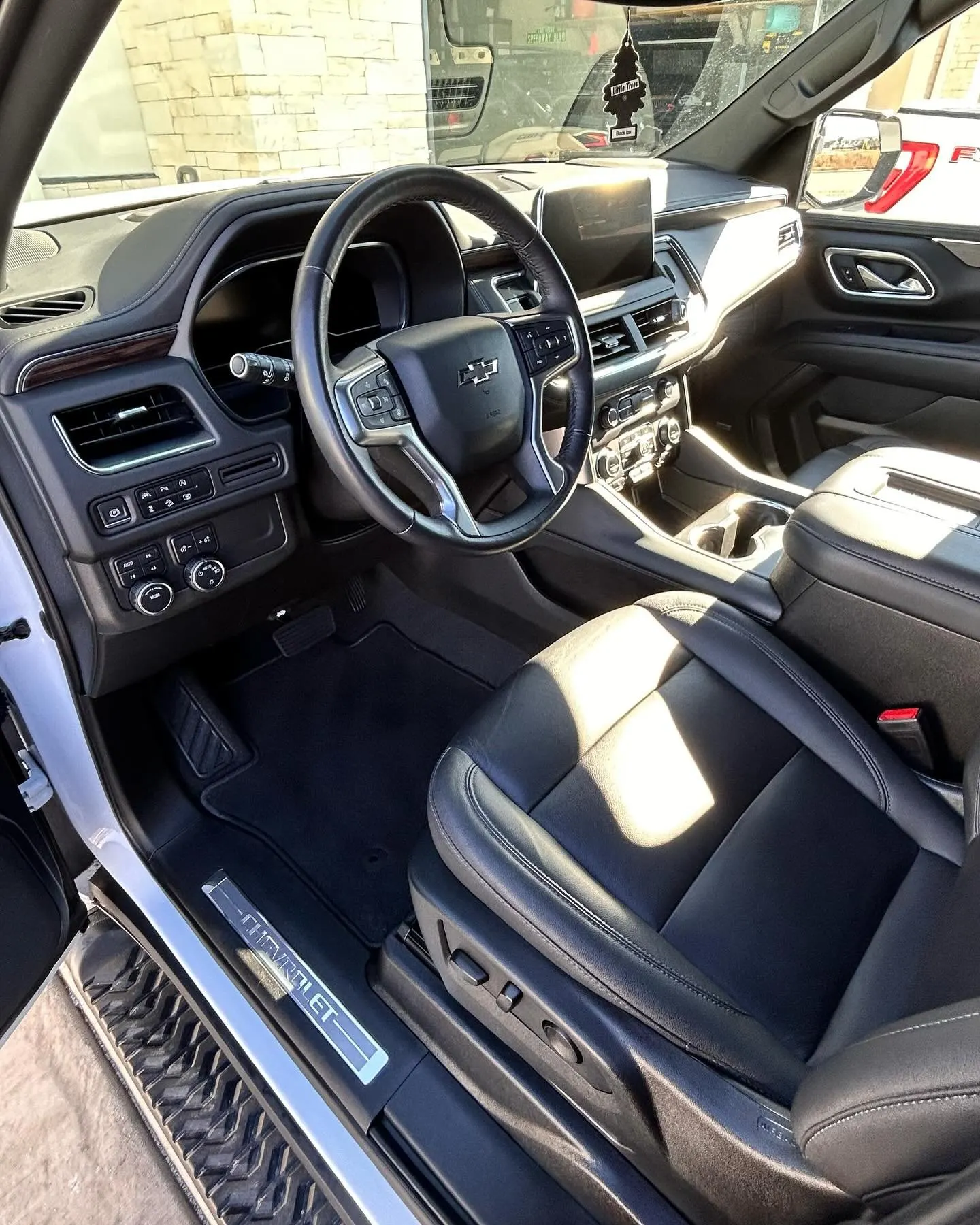 The detailed black cockpit of a Chevy Tahoe, driver door open