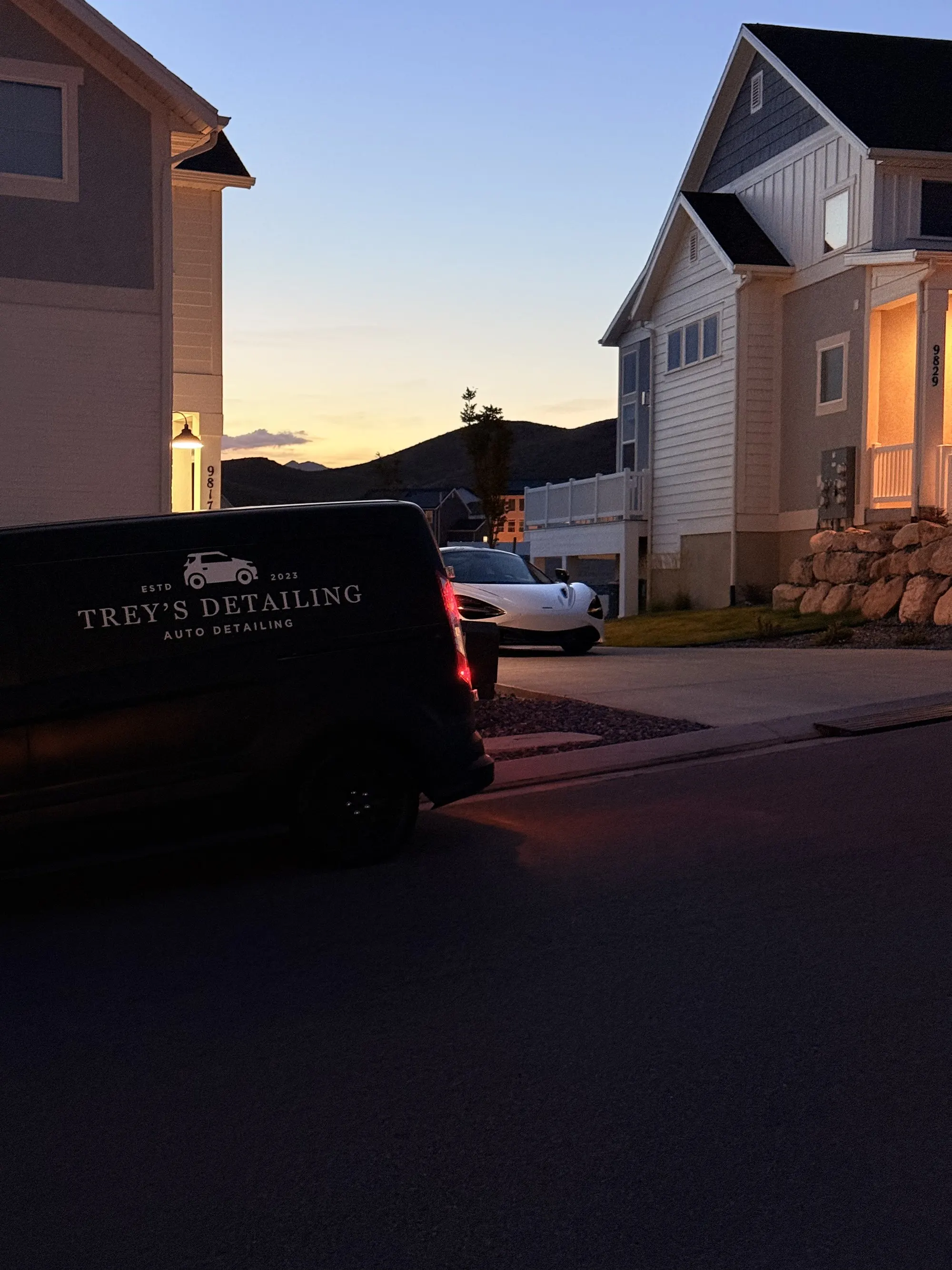 The Trey's Detailing van parked in a client neighborhood at dusk, a white McLaren behind it