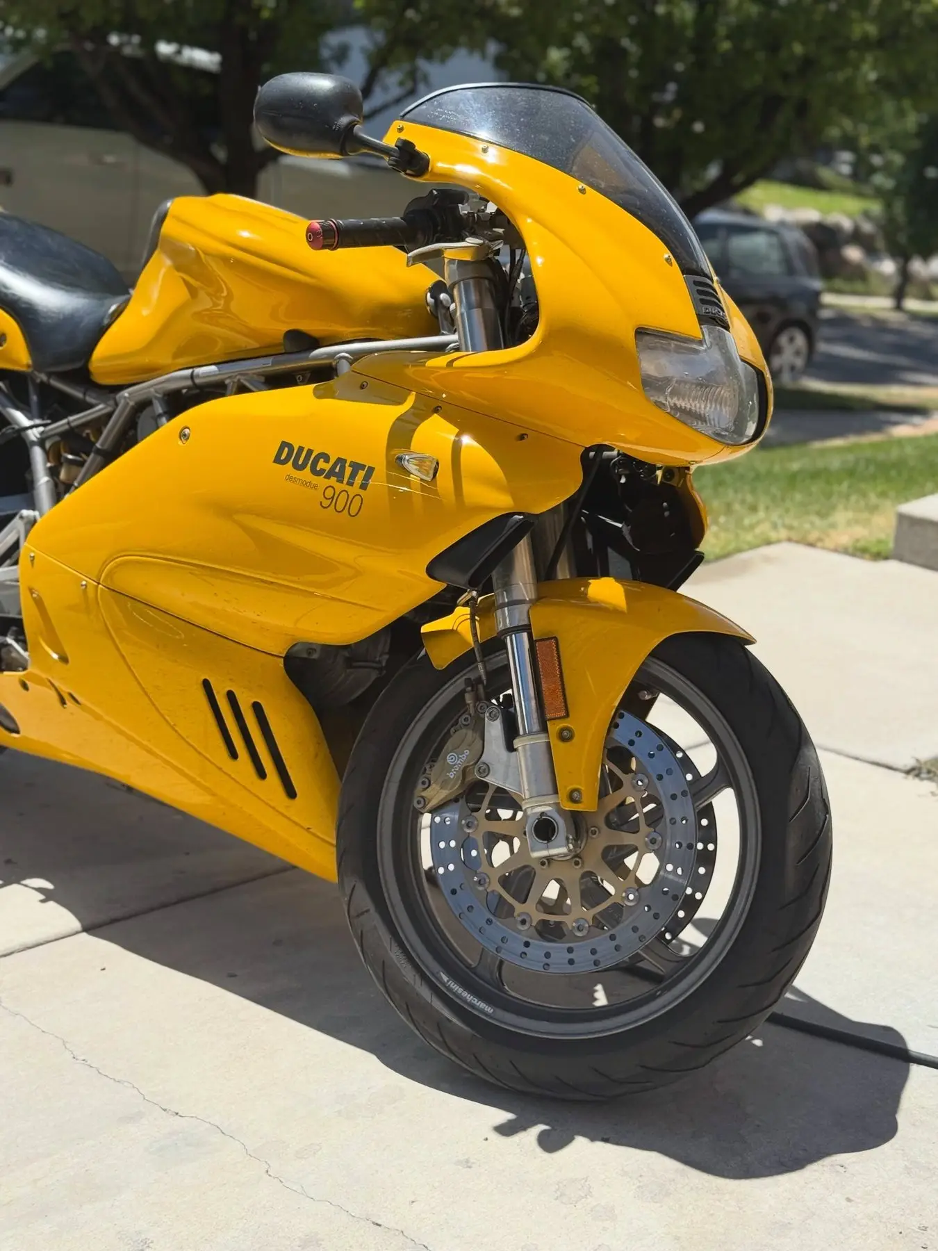 A yellow Ducati 900 parked in a driveway after a wash
