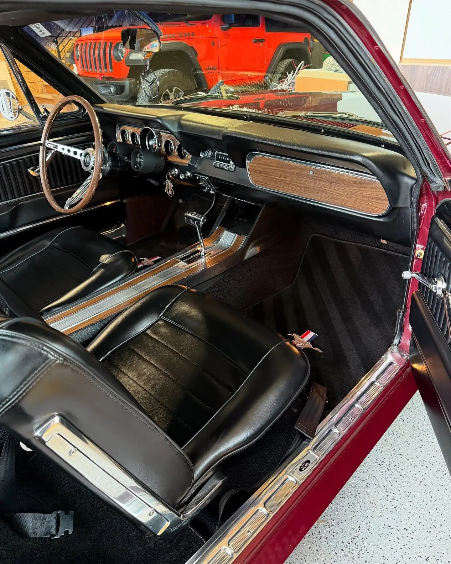 The interior of a 1966 Mustang, wood-rimmed wheel and black leather