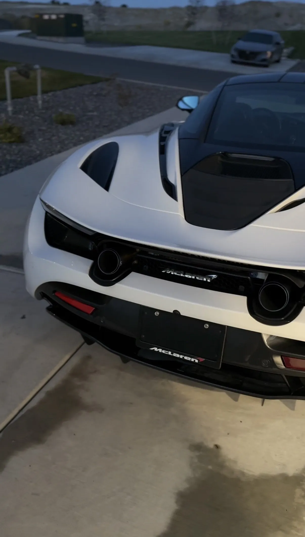 A white McLaren 765LT three-quarter at night, rear wing in frame