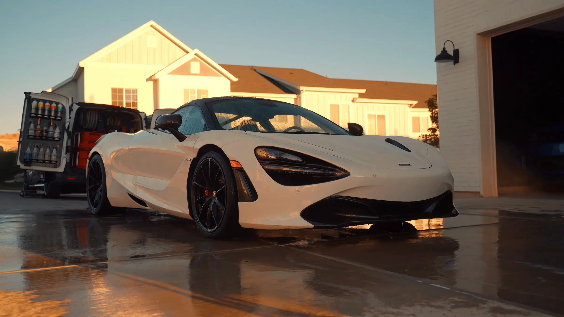 A white McLaren 720S in a driveway beside the open Trey's Detailing van