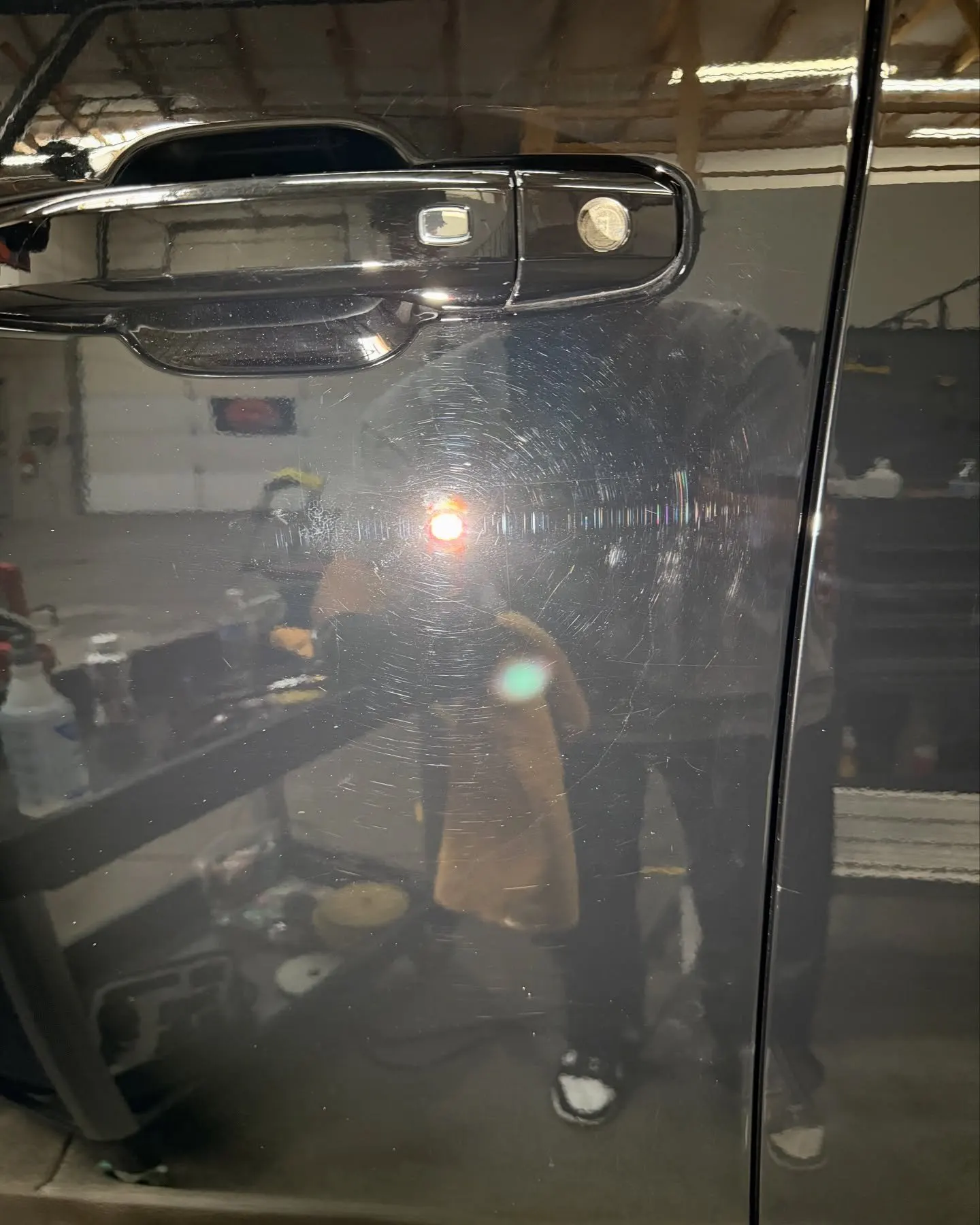 Dark tinted door glass mid-install, the technician reflected in the film