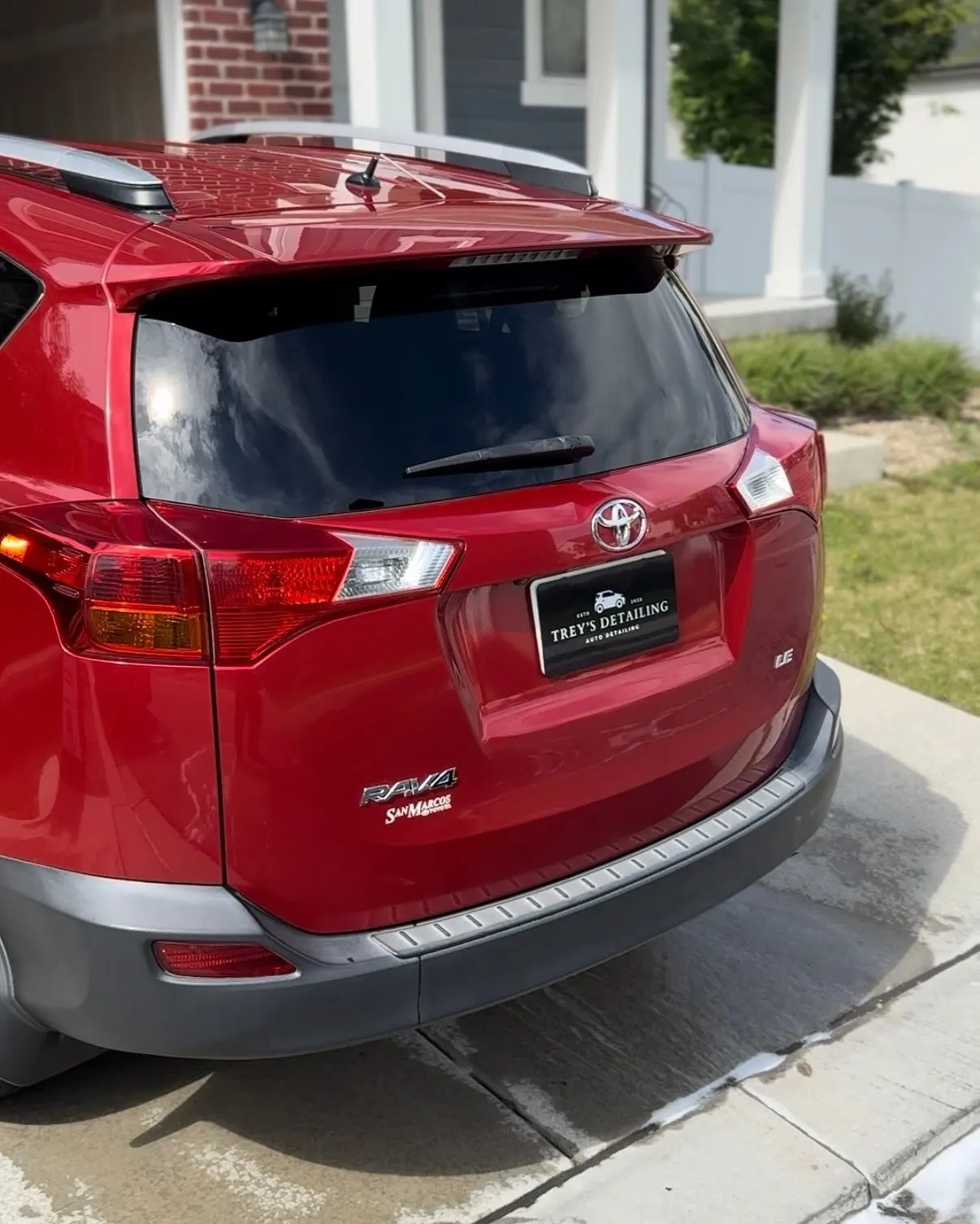 The wet rear three-quarter of a red Toyota RAV4